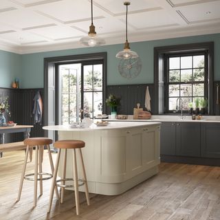 A grey kitchen with cream kitchen island with rounded corners, breakfast bar and wood bar stools