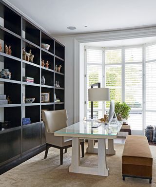 Home office with desk and chair and bench and floor to ceiling black shelving