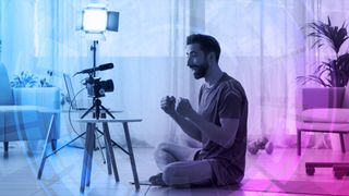 A man sitting on a yoga mat talking to a camera
