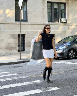 Woman wearing a black top and white miniskirt.