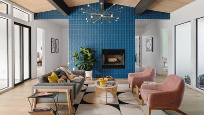 Living room with blue tiled fireplace, oak flooring, grey and pink armchairs and neutral patterned rug