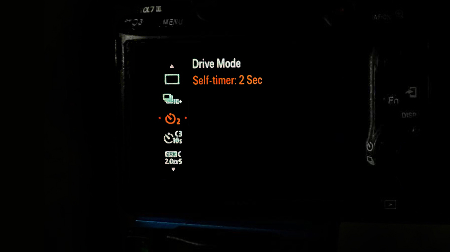 Close-up of a Sony camera screen displaying the "Drive Mode" settings with "Self-timer: 2 Sec" selected in orange
