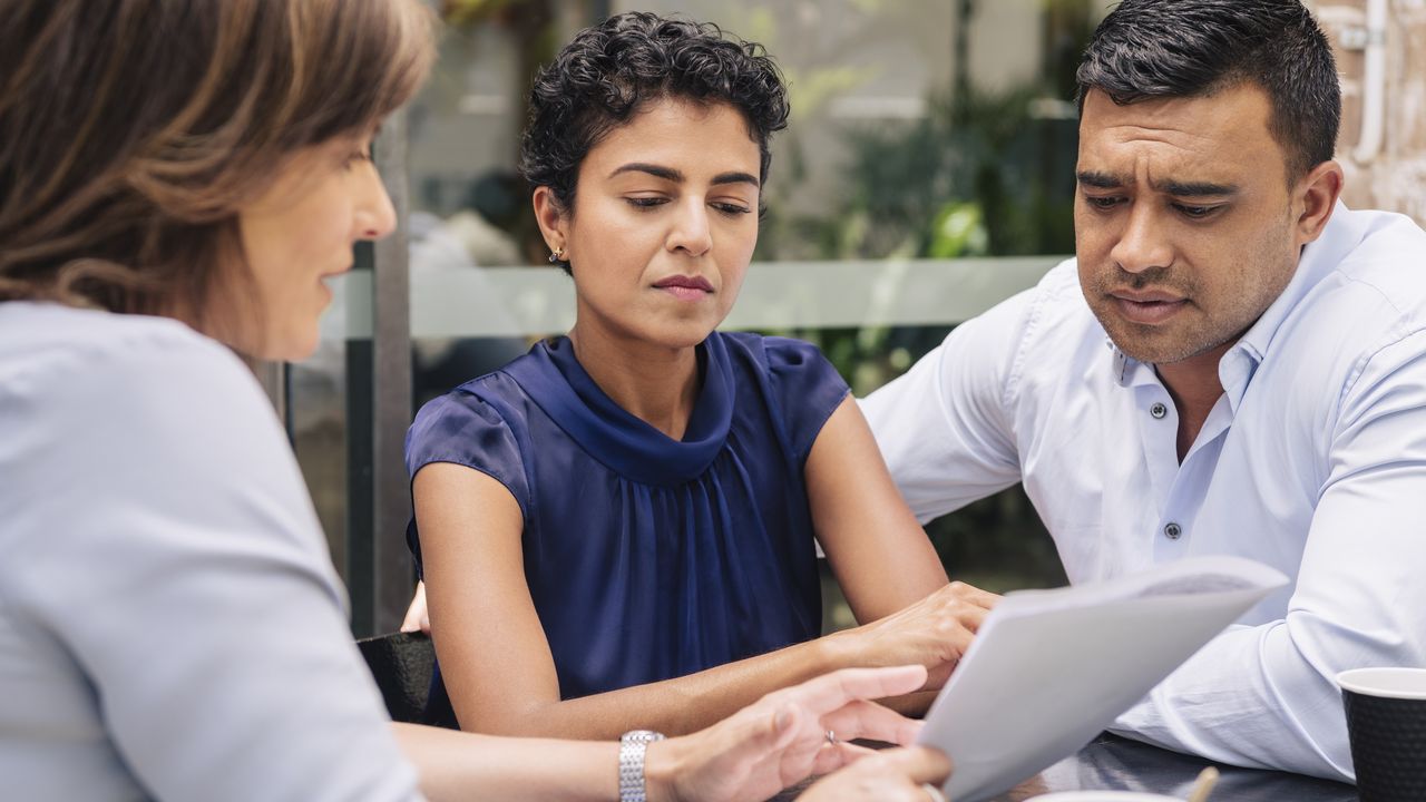 A financial adviser works with a skeptical-looking couple.