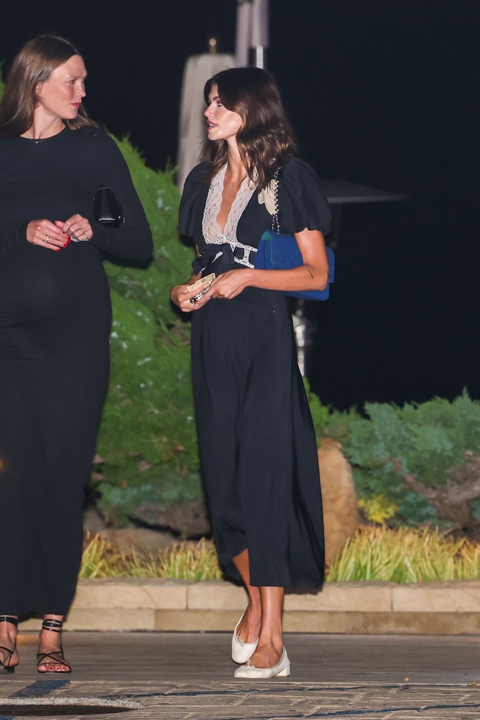 Kaia gerber wears a black maxi dress with white ballet pumps.