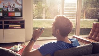 Man holding amazon fie tv stick remote while watching TV