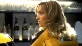 Uma Thurman in a yellow leather jacket looking over her left shoulder.