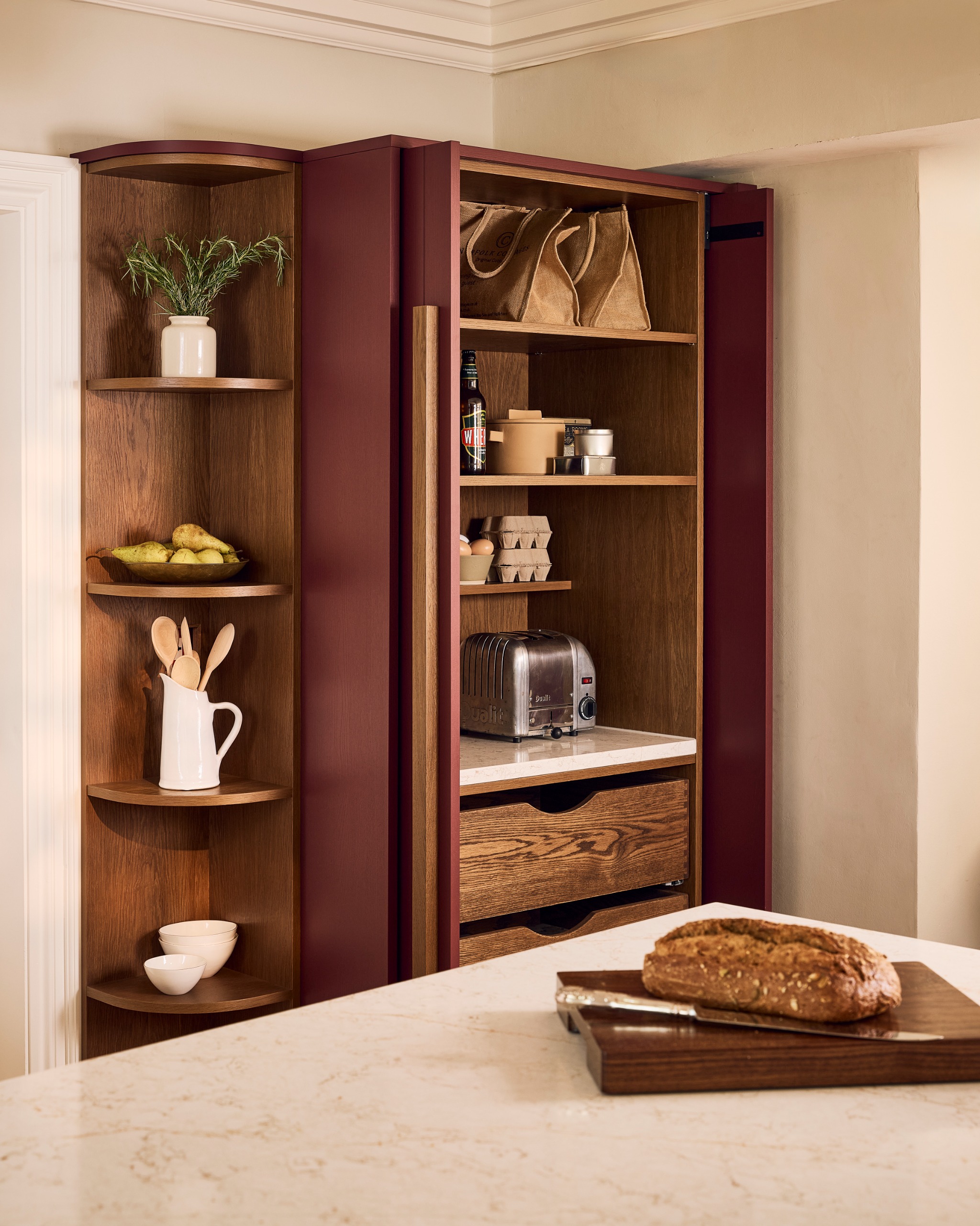 pocket door pantry in burgundy with with curved shelves and hidden appliances