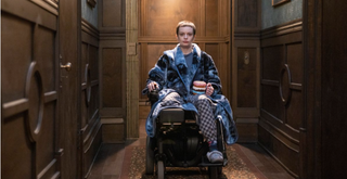 Anya in a wheelchair wearing a dressing gown