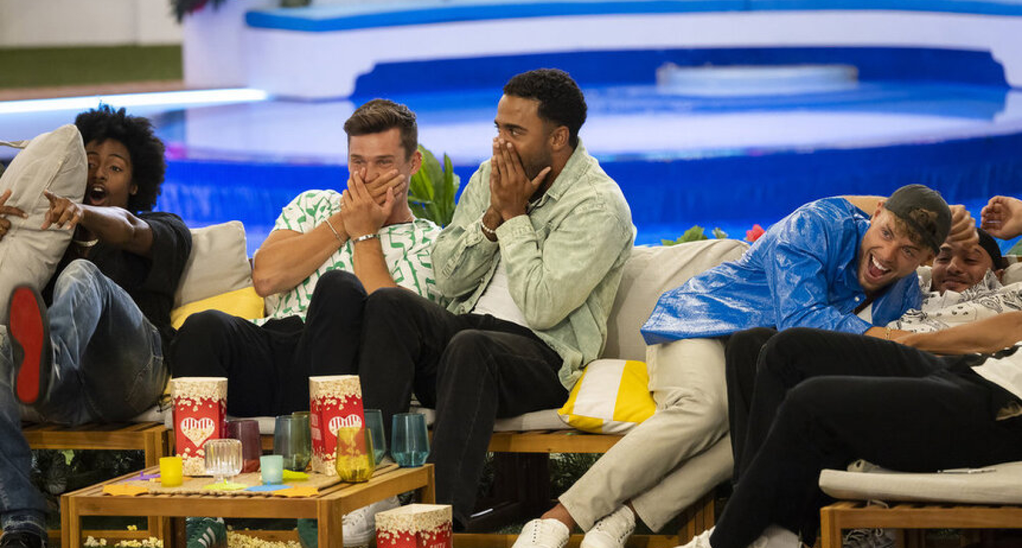 the men of love island usa season 6 laugh and looked shock covering their mouths while sitting on the couch and watching movie night