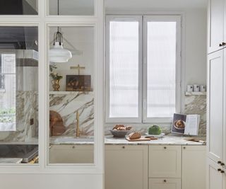 kitchen with cream cabinets and marble backsplash in space with glazed partition walls