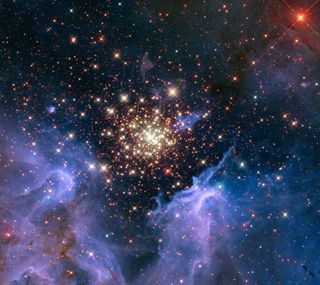 A young, glittering collection of stars looks like an aerial burst. The cluster is surrounded by clouds of interstellar gas and dust—the raw material for new star formation. The nebula, located 20,000 light-years away in the constellation Carina, contains