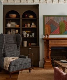living room with large gray armchair and shelf full of antiques