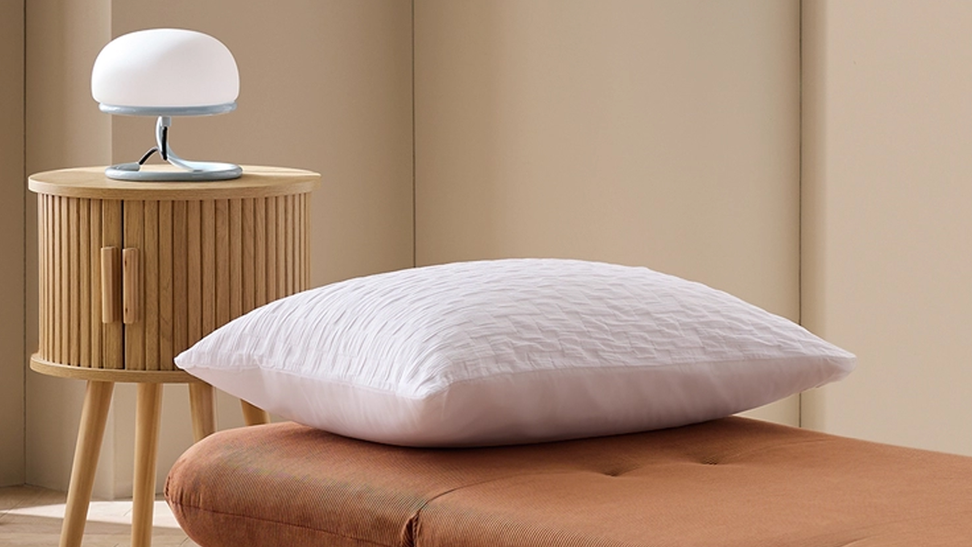 Habitat Benji Chair Bed with a white pillow on top and a round wooden bedside table with a white lamp
