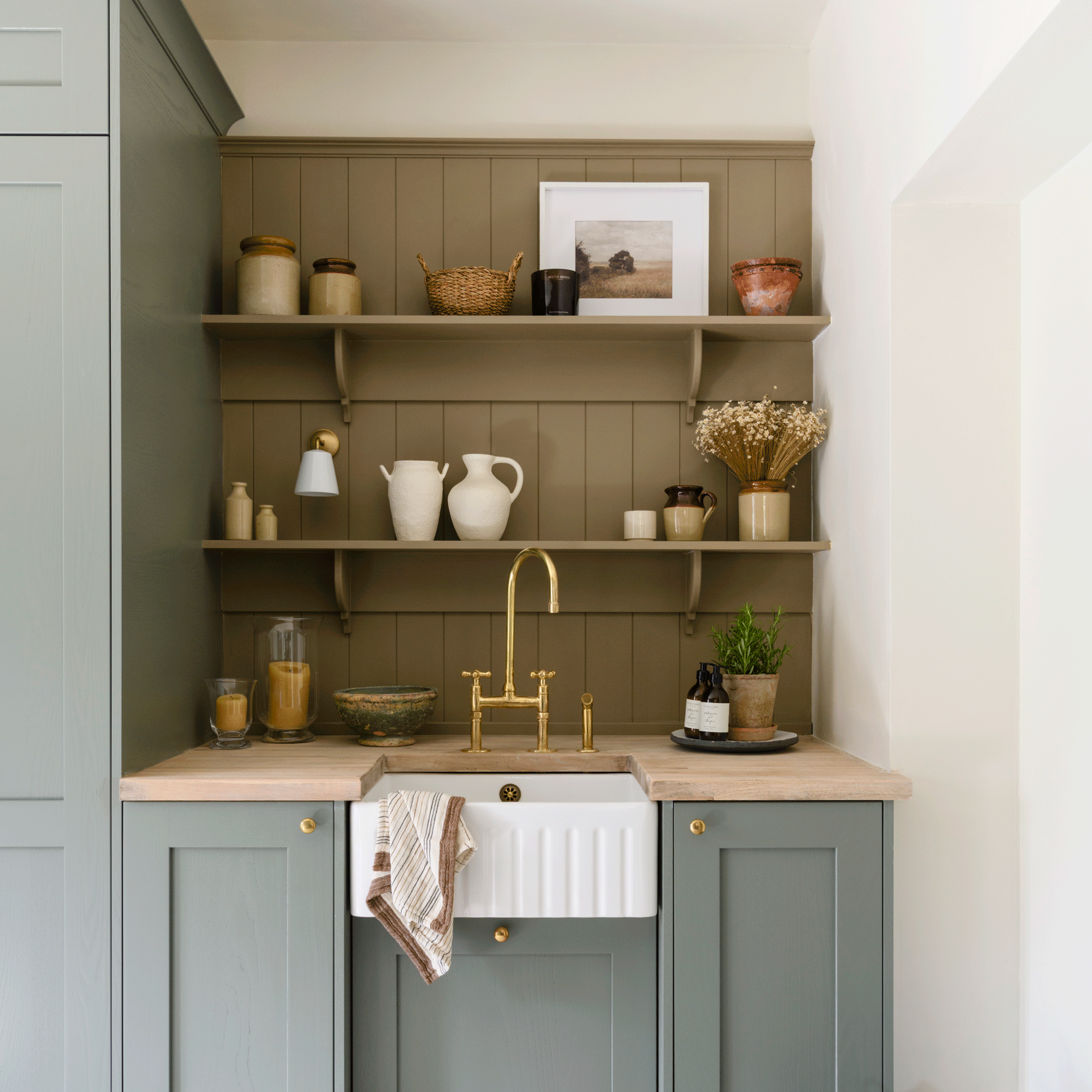 a utility room with small Belfast sink, open shelving and fitted cupboards