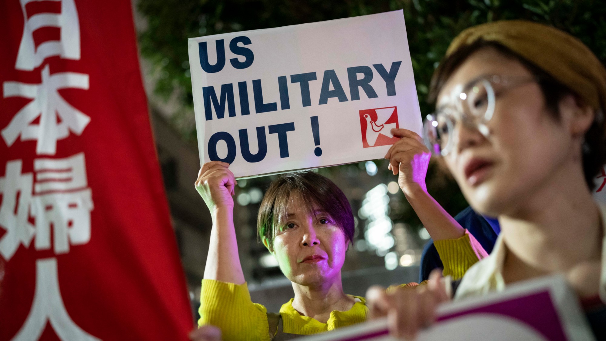 A woman holds up a placard reading 'US military out' during a protest against the killing of a woman in Okinawa