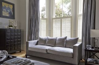 living with large windows and high ceilings, cafe style blinds and a grey sofa