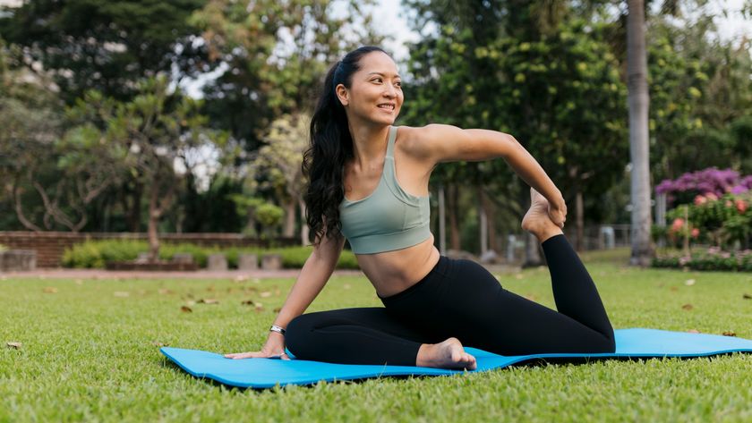 Woman outdoors on yoga mat performing pigeon pose