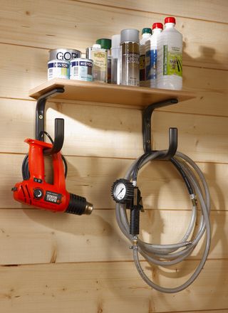 Shelf with tins and bottles with supports with power tools and hose hanging on them