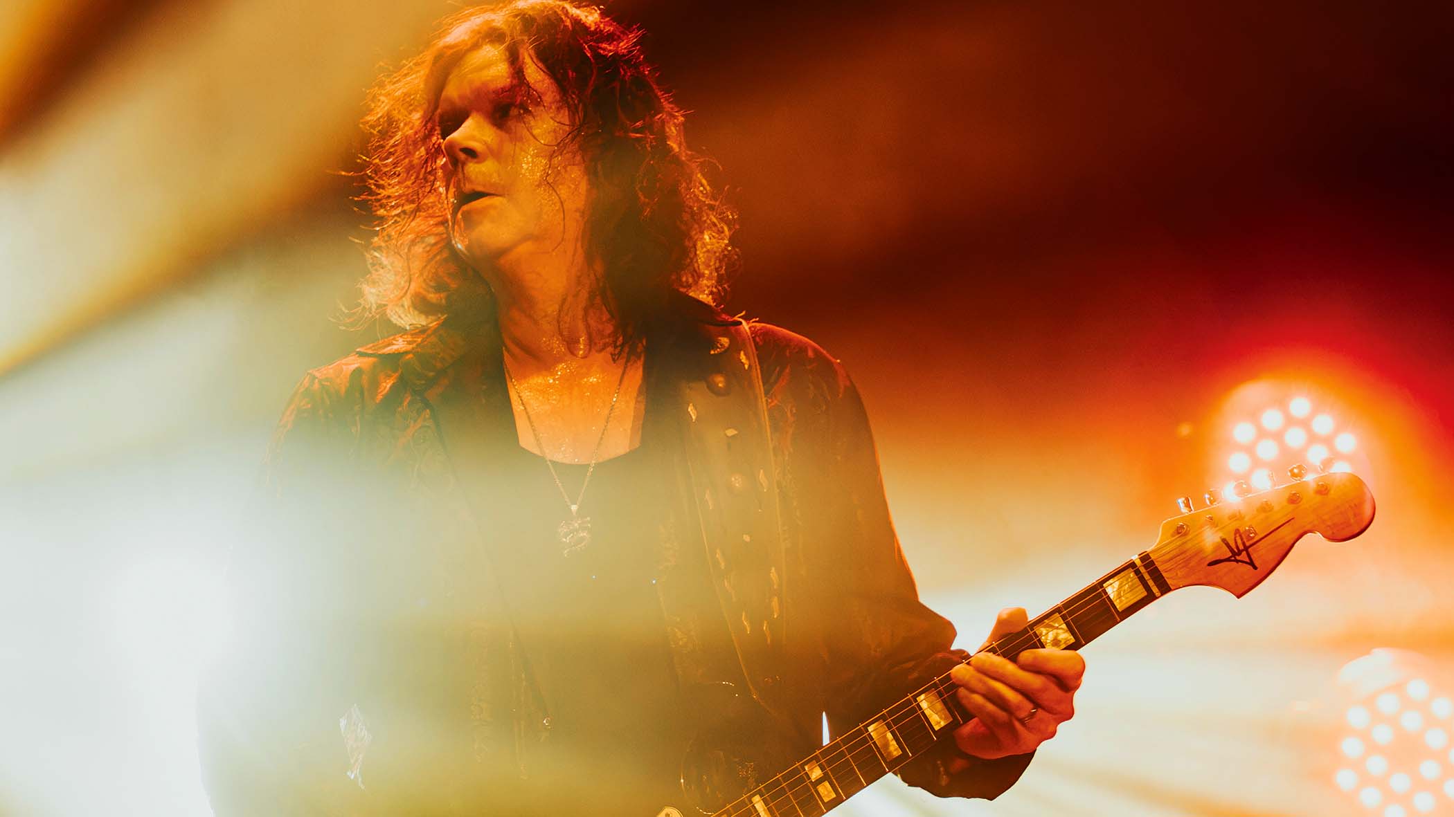 John Norum of Europe performs on a stage light up in gold.