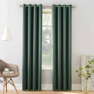 Green curtains hanging on a gold curtain rail in a living room.