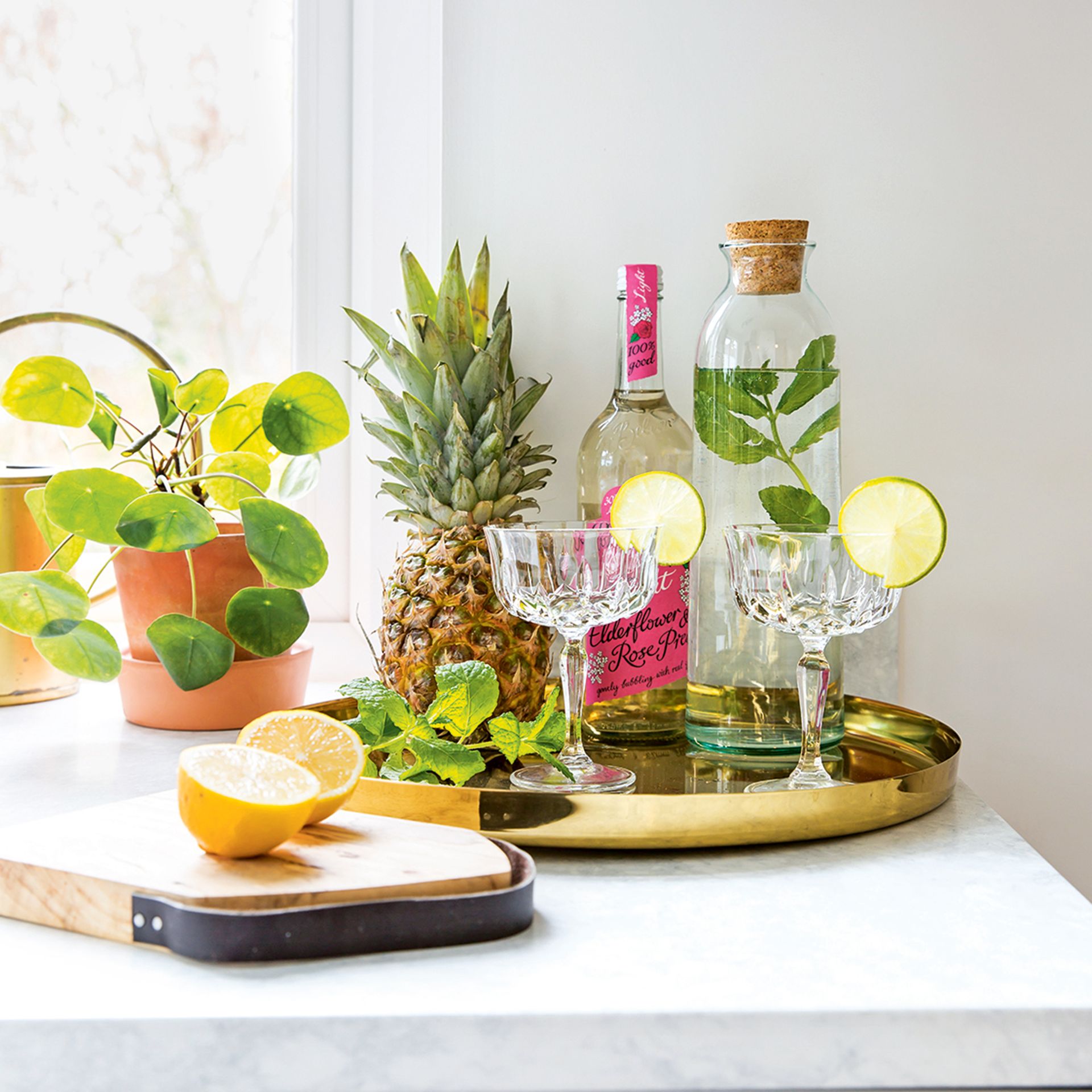 Cocktail tray in kitchen with lemons, mint and pineapple