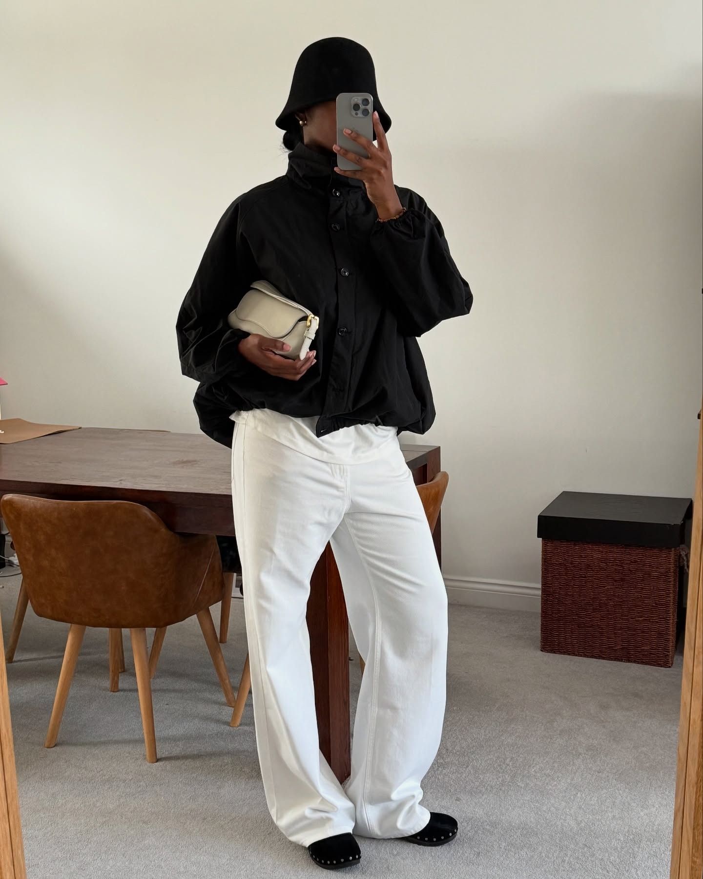 Influencer @nlmarilyn wears white jeans with black flats, a black funnel neck jacket and a black hat.