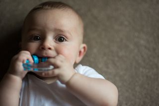 Which teeth come in first? Image shows baby sucking on teething ring