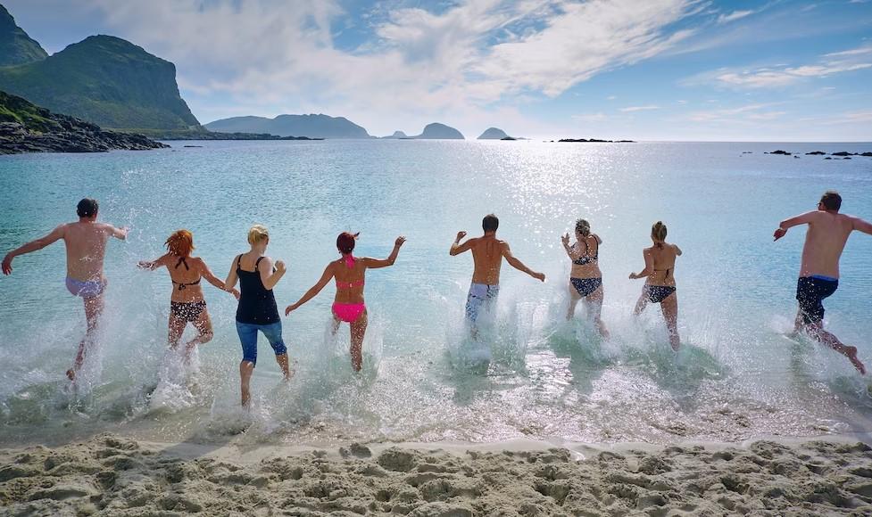  A group of friends running into the sea at the beach 