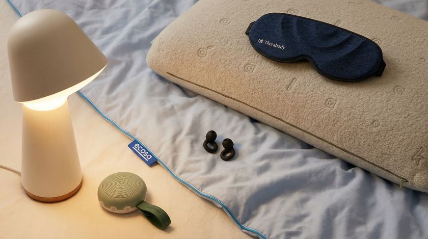 A smart lamp, quilt, white noise machine, pillow and eye mask on the floor