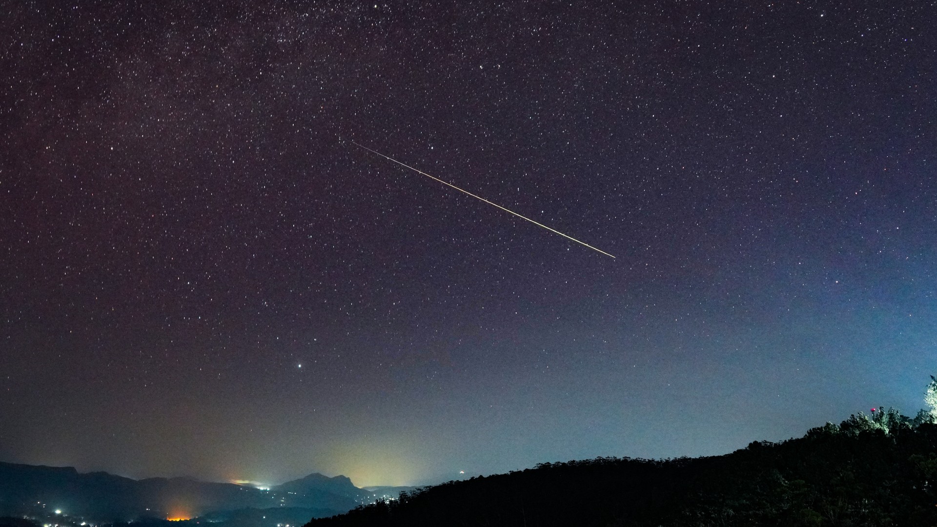 Eine Lichtlinie kreuzt den Nachthimmel