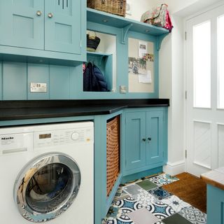 utility room with printed tiled flooring and blue cabinets