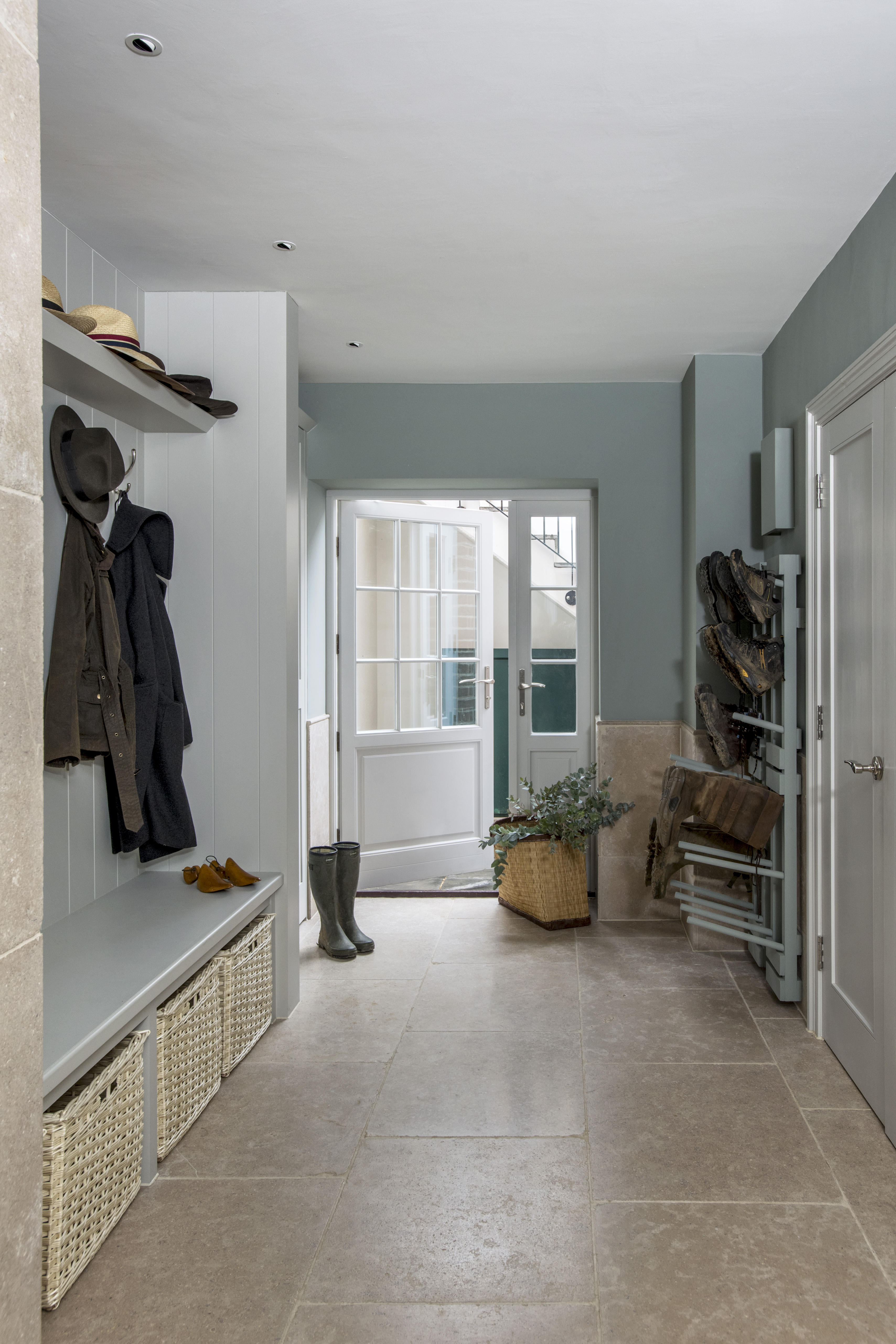 long narrow mudroom with bench seat, coat hooks and shelf and pale walls and tile floor