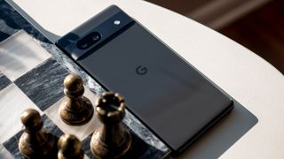 The Charcoal Google Pixel 7a next to a marble and metal chess board