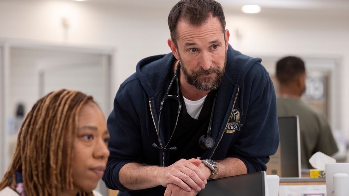 Krystel McNeil and Noah Wyle stand around a medical station listening intently in The Pitt S1 E1 - &quot;7:00 AM.&quot;