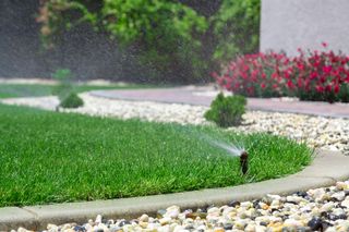 Garden Sprinkler watering a lawn beside a gravel pathway