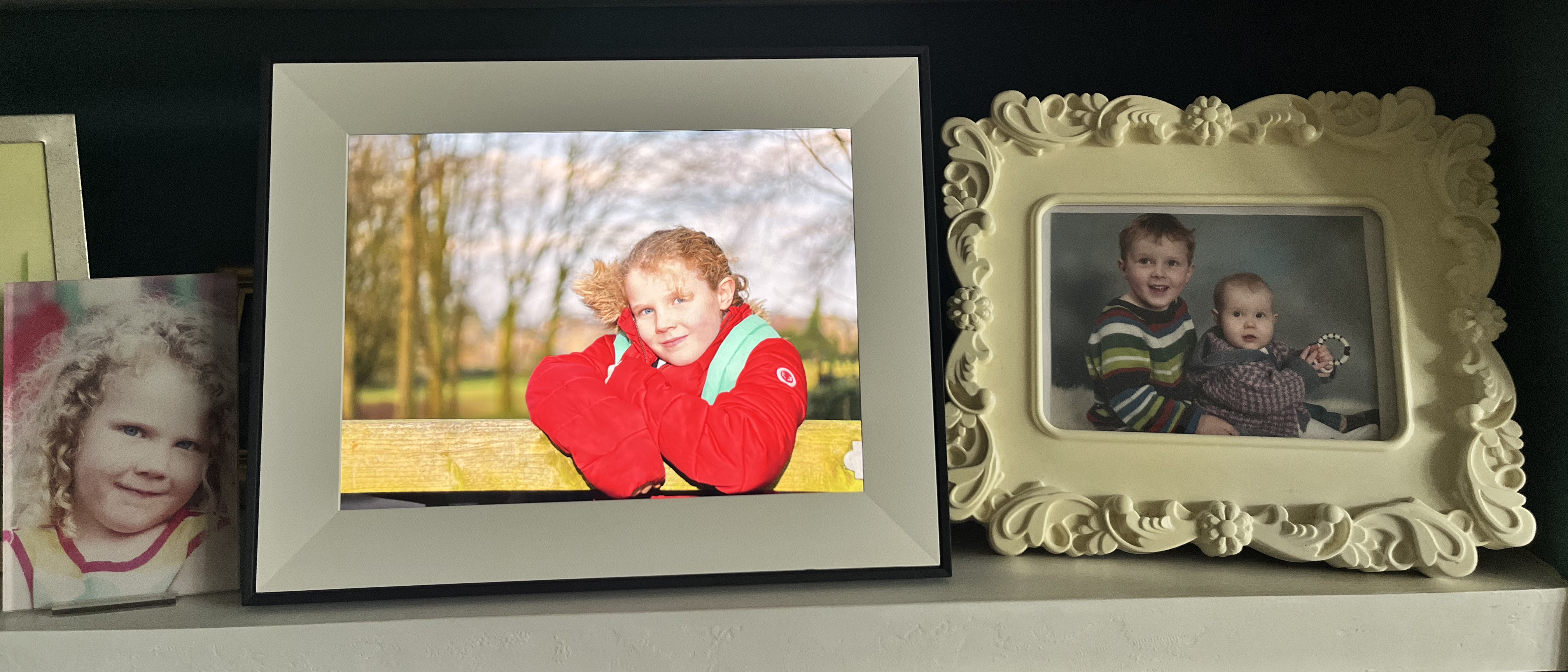 Aura Aspen digital photo frame on bookshelf with regular framed photographs