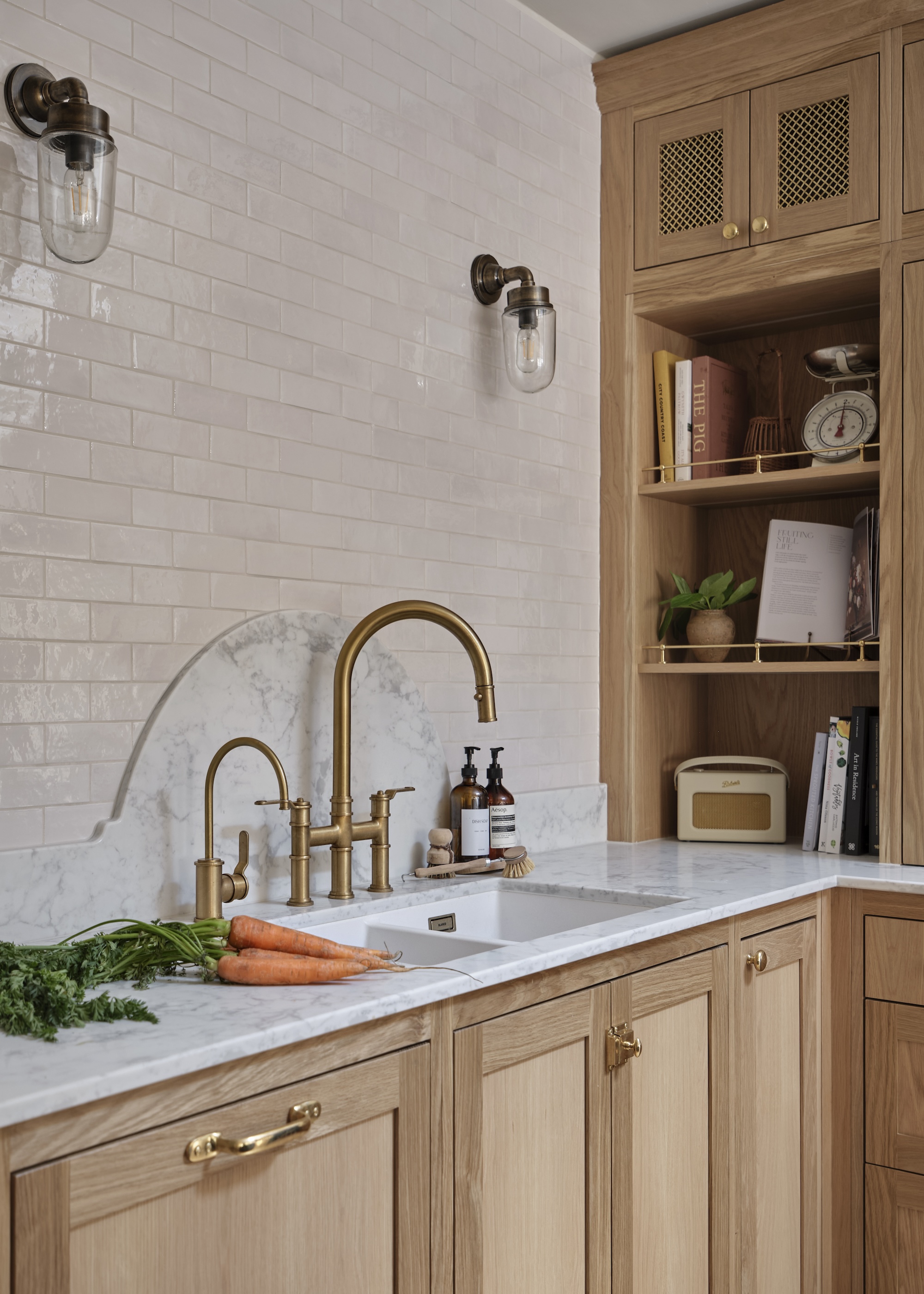 A shot of a corner of an oak kitchen with bottom cabinets as well as a a storage space with open shelving that reaches the kitchen ceiling