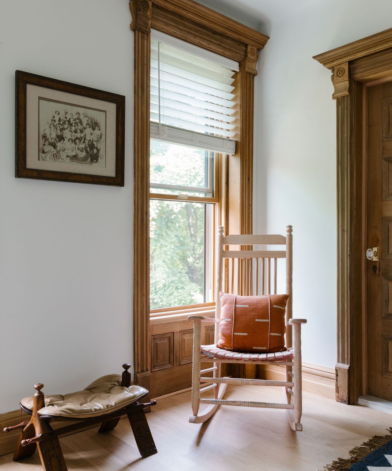 A brownstone bedroom with a rocking chair in the corner of the room and a framed photo
