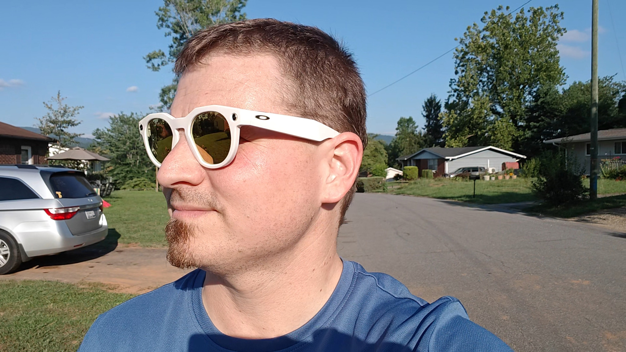Walking through a neighborhood while wearing warm white Oakley Meta HSTN smart glasses