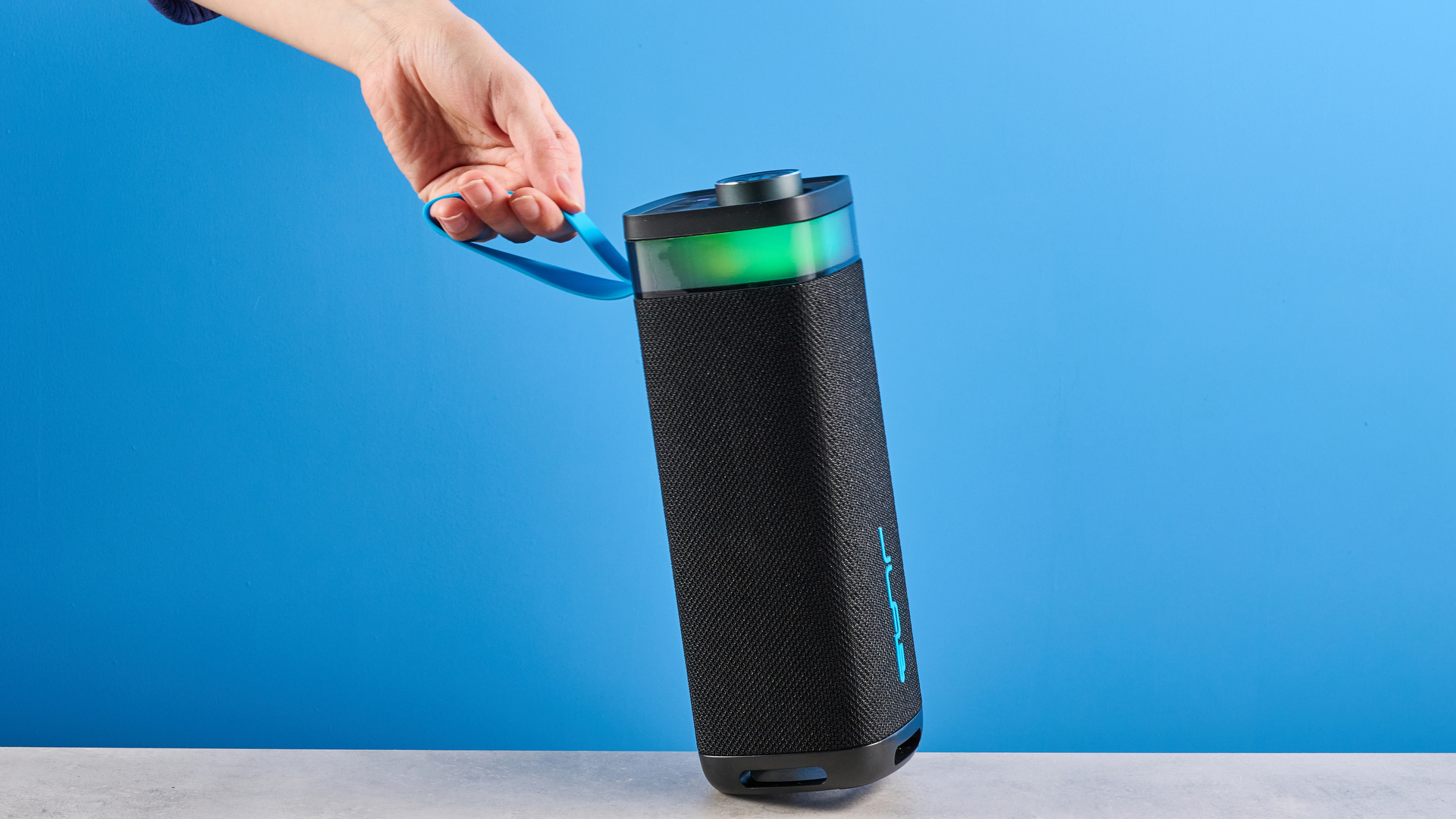 the jlab jbuds party speaker with LED rainbow lights photographed against a blue background