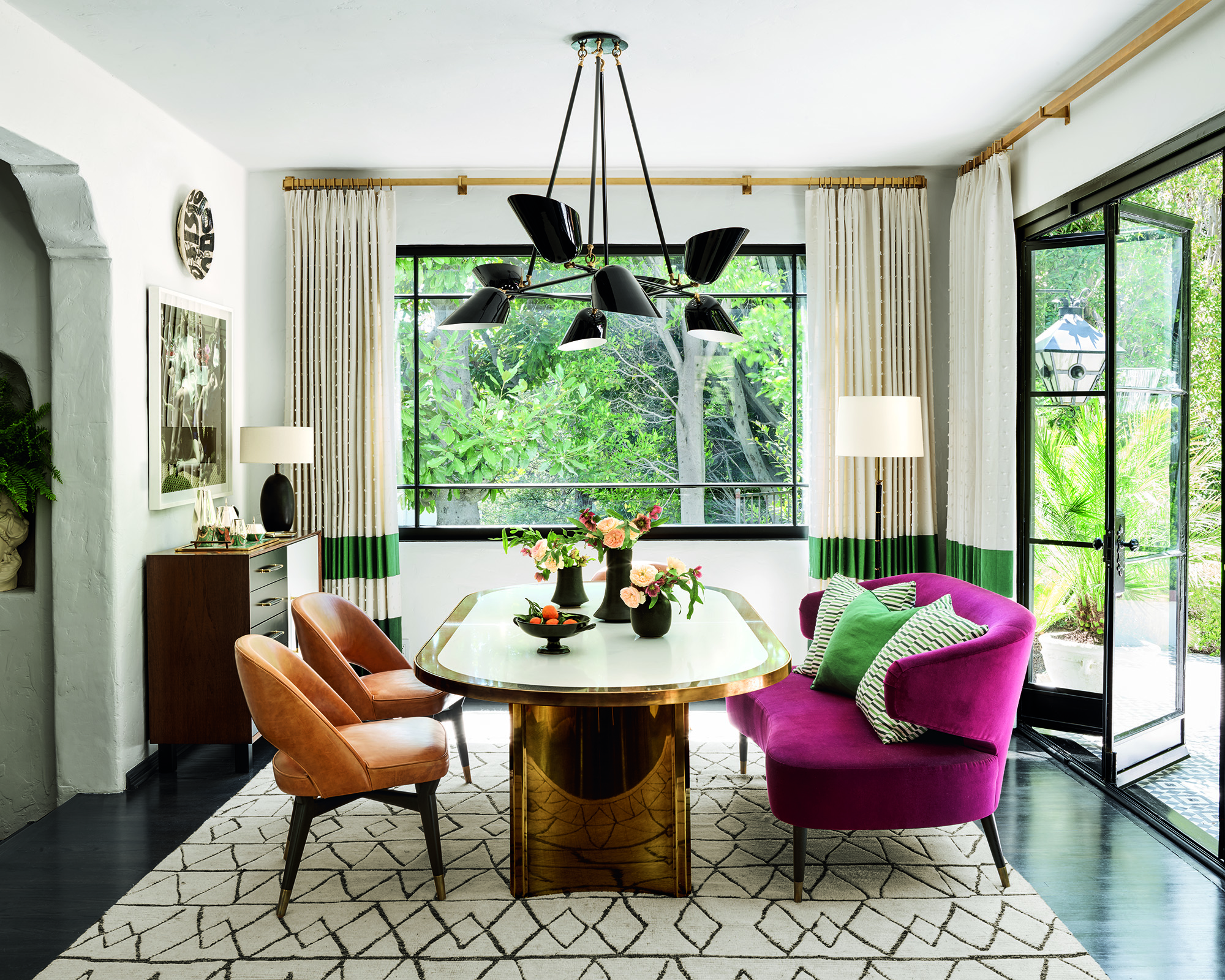 dining room with oval gold table in the middle, a pink sofa on one side and orange chairs on the other