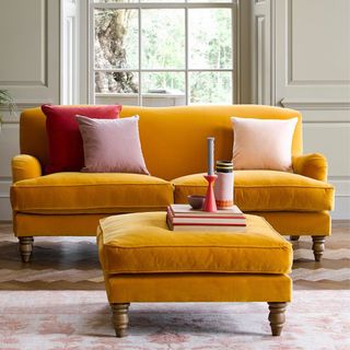 A bright yellow sofa with a matching yellow footstool