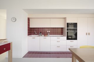 A kitchen with red walls and pink cabinets