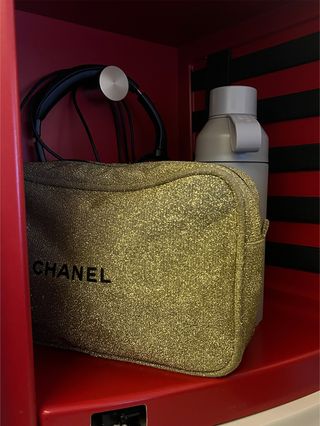 A photo of a Chanel gold makeup bag, water bottle, and headphones on an Air France flight.