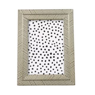 A white and gold herringbone photo frame with a black and white polka dot picture
