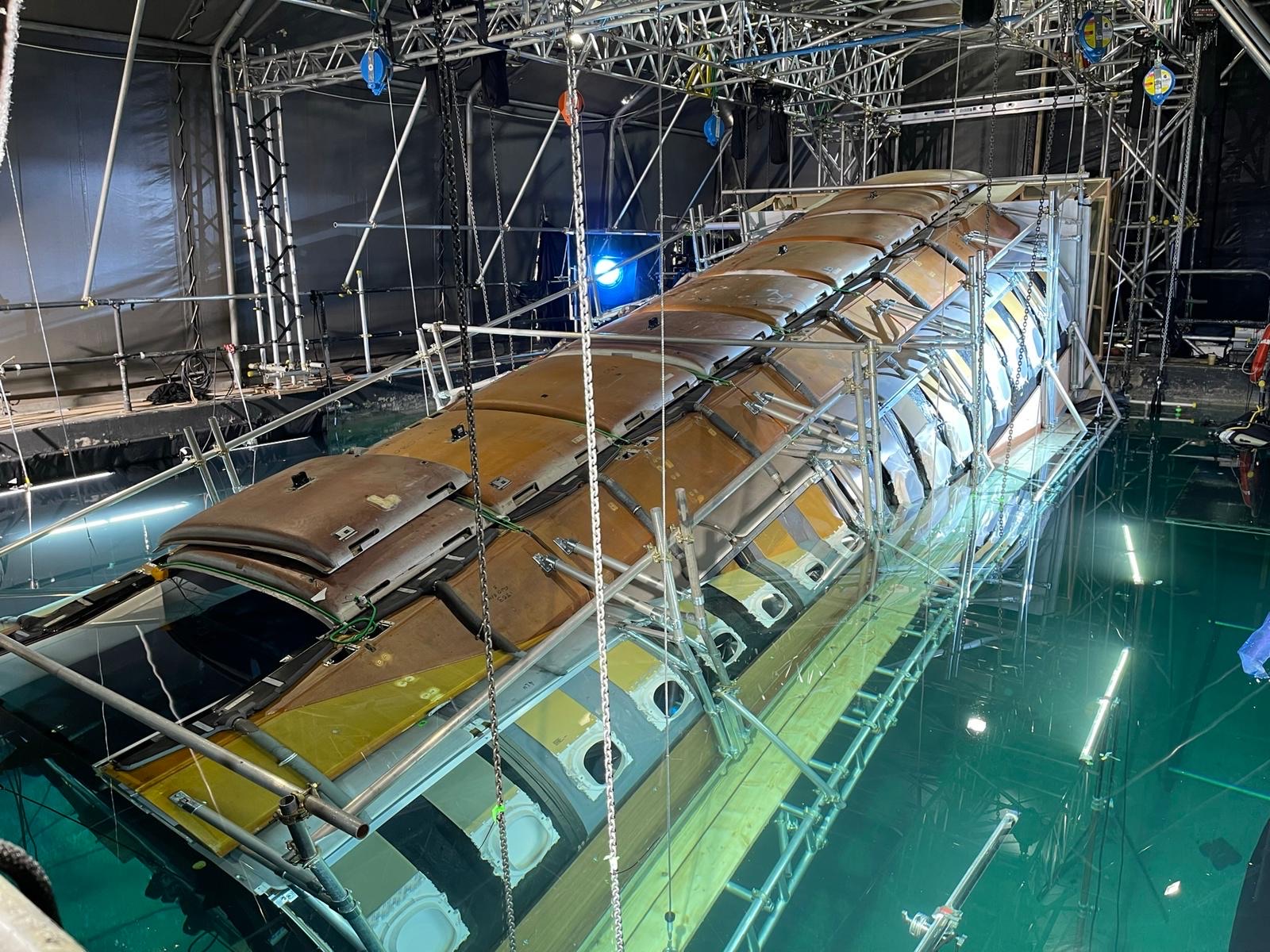 An airplane chassis being lowered into a pool of water