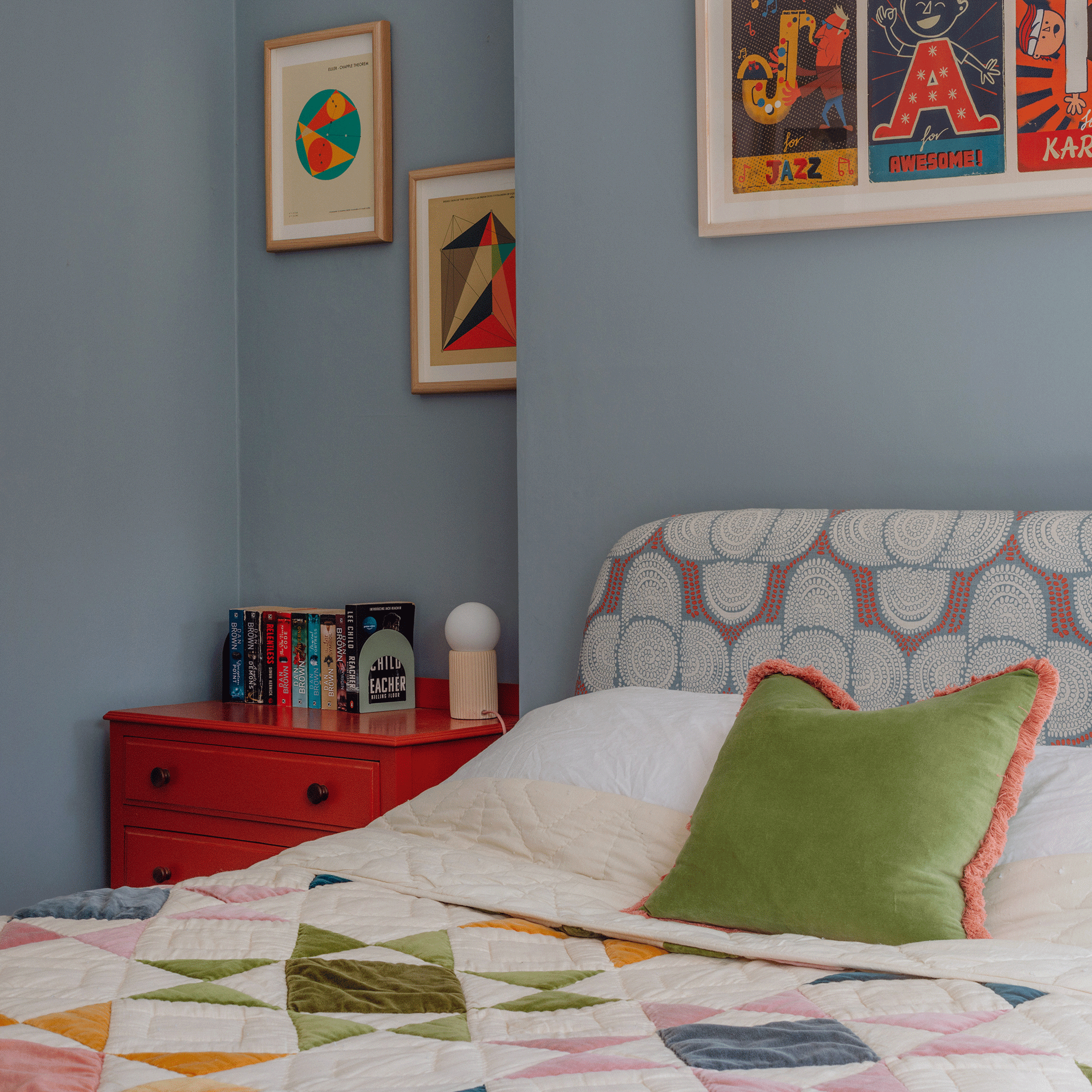 Blue bedroom with patterned headboard and red dresser