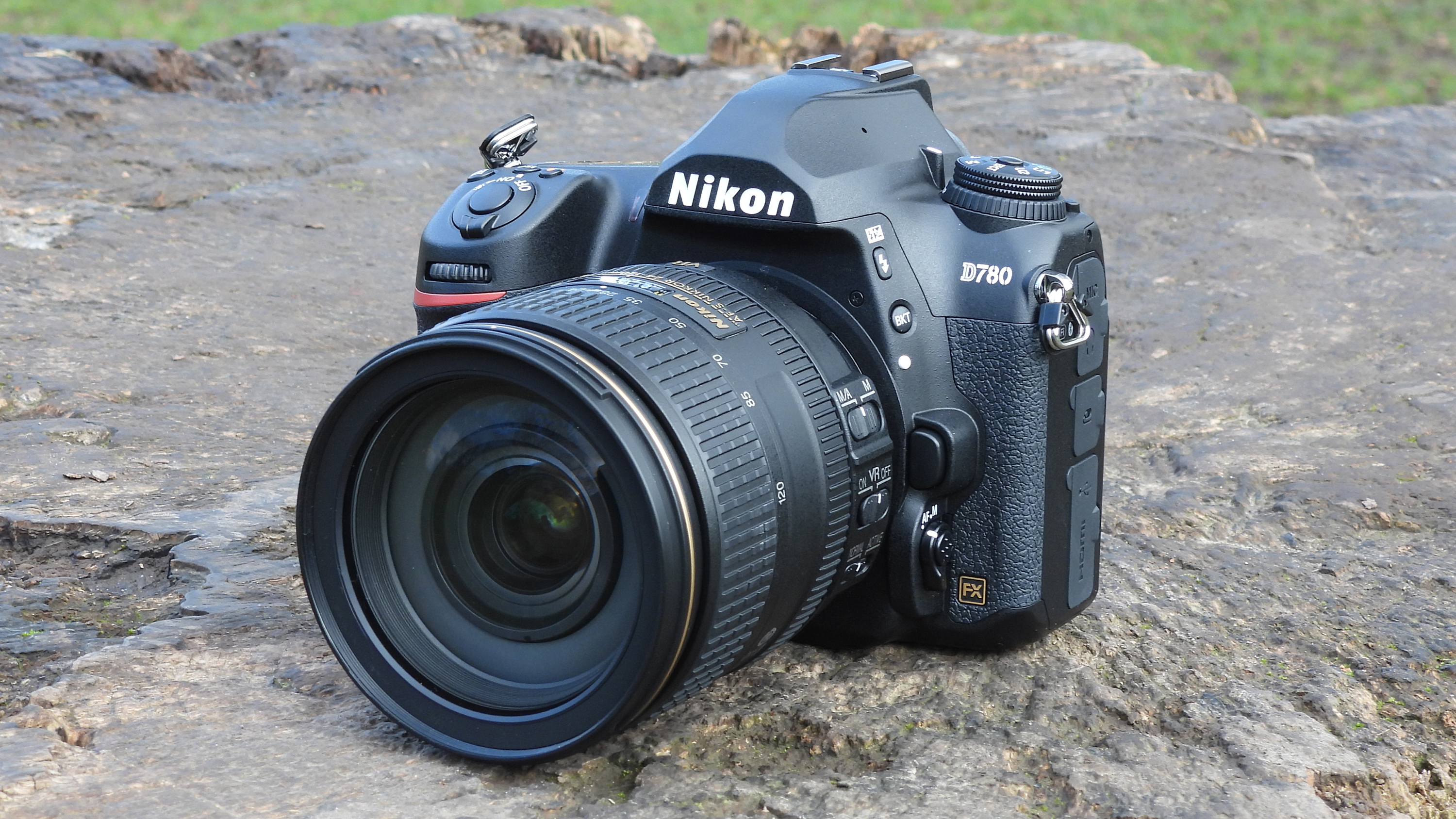 En Nikon D780 ligger utomhus på en grå sten.