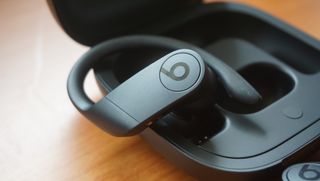 A close up of the Beats Powerbeats Pro pictured in their charging case on a wooden surface