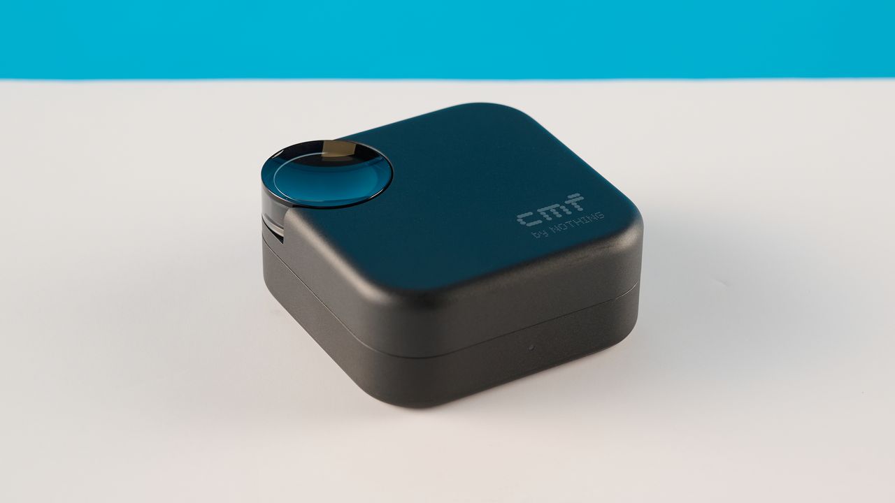 CMF Buds 2 in Dark Gray photographones on a gray table in front of a blue background